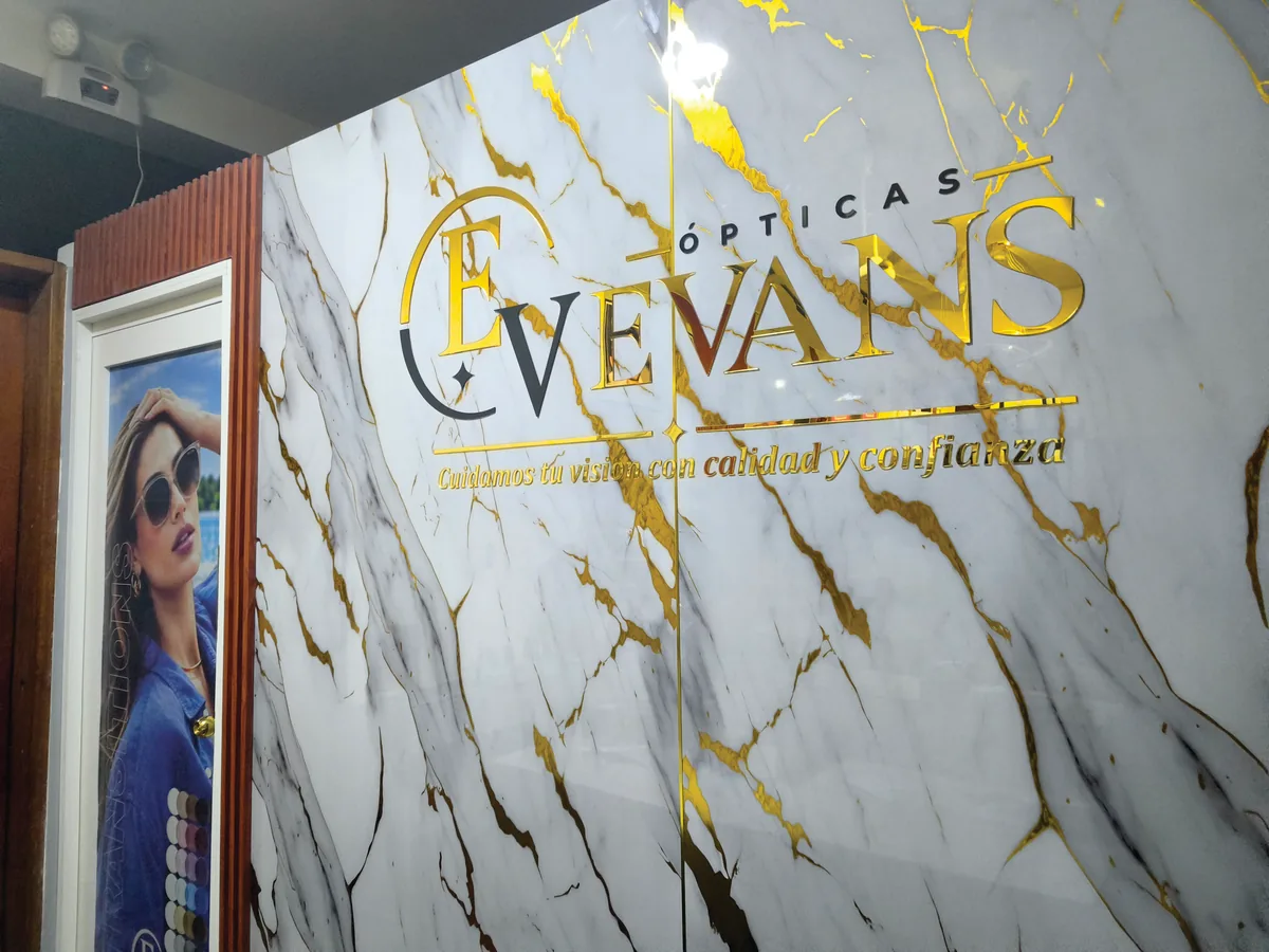 Letras doradas de Ópticas EVEVANS en una pared de mármol