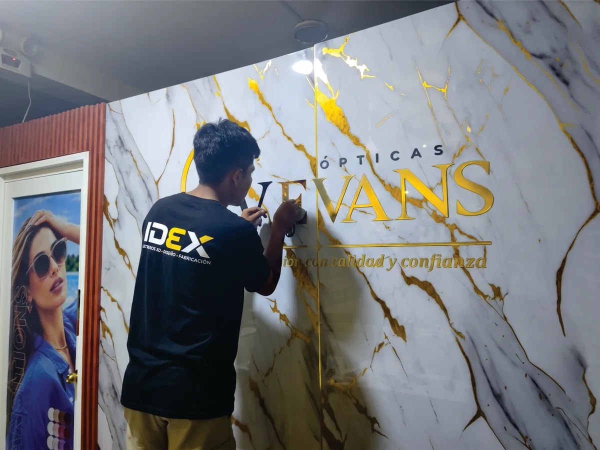 Instalador de IDEX colocando letras doradas en Ópticas EVEVANS